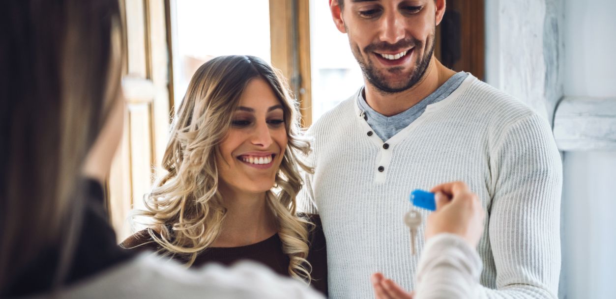 A couple receives keys, smiling happily as they make a transaction or celebrate a new home.